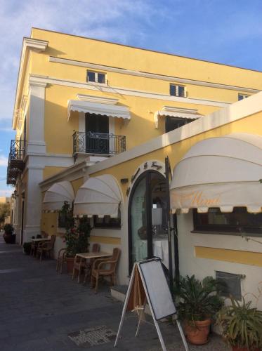 a building with tables and umbrellas in front of it at Hotel Mezzatorre in Ventotene