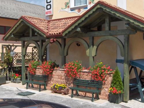 a gazebo with benches in front of a building with flowers at Hotel Allo Zodiaco in Andalo