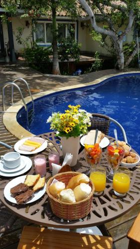 een tafel met eten en drinken op een tafel bij een zwembad bij Ferradura Parque Pousada in Búzios
