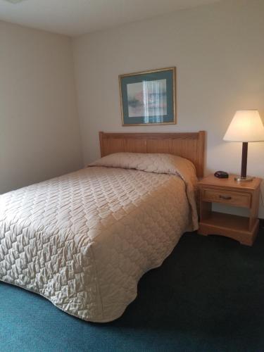 a bedroom with a bed and a table with a lamp at Affordable Suites Gastonia in Gastonia