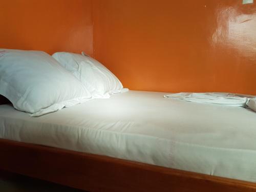 a bed with white sheets and pillows in a room at Maison Rose in Douala