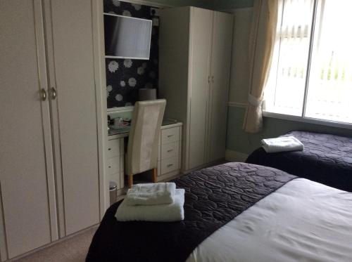 a bedroom with two beds and a desk with a tv at Alma Lodge Guest House in Plymouth