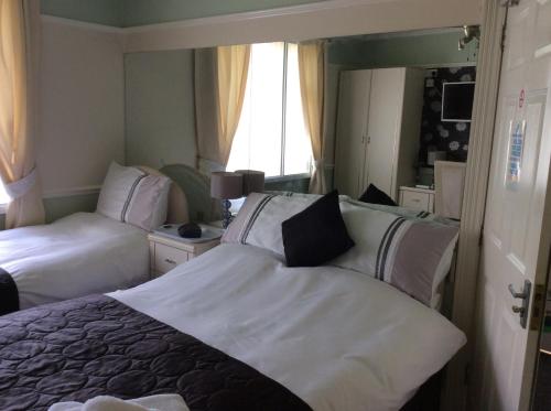 プリマスにあるAlma Lodge Guest Houseのベッド2台と鏡が備わるホテルルームです。