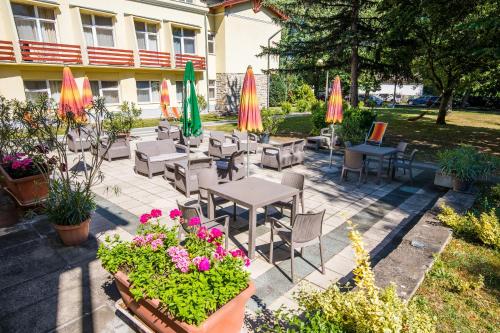a patio with tables and chairs and umbrellas at Hello Balcsi Apartmanház in Tihany