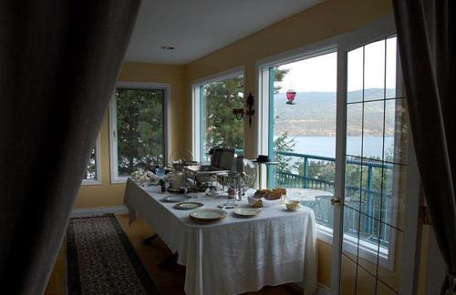 ein Esszimmer mit einem Tisch mit einer weißen Tischdecke in der Unterkunft Eagle's Nest B&B in Lake Country