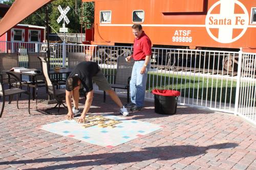 two men playing a game on a rug in front of a train at Woodrow House Bed & Breakfast in Lubbock