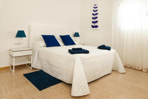 a bedroom with a white bed with blue pillows on it at Apartamento Filla in Puerto del Carmen