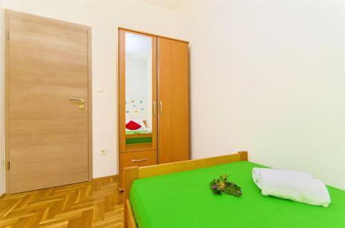a bedroom with a green bed and a door at Apartments Pava in Okrug Donji