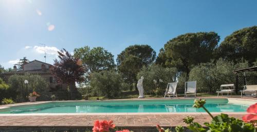 a large swimming pool with two chairs and trees at Agriturismo Podere Caggiolo - Swimming Pool & Air Conditioning in Marciano