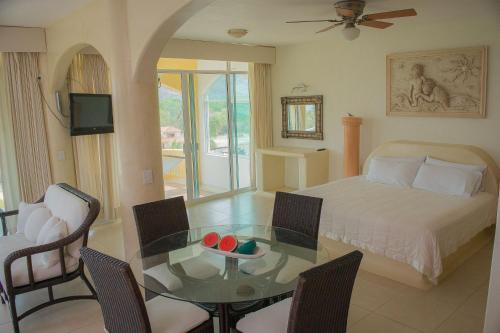 a bedroom with a bed and a table and a dining room at Bungalows Arena Dorada in Zihuatanejo