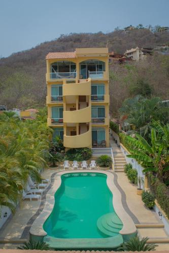 a hotel with a swimming pool in front of a building at Bungalows Arena Dorada in Zihuatanejo