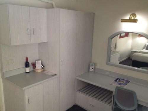 a room with a desk and a mirror and a bed at Adelaide Royal Coach in Adelaide