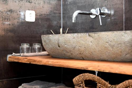 uma casa de banho com um lavatório de pedra numa prateleira de madeira em Gastenverblijf Kleinkamperfoelie em Gorssel