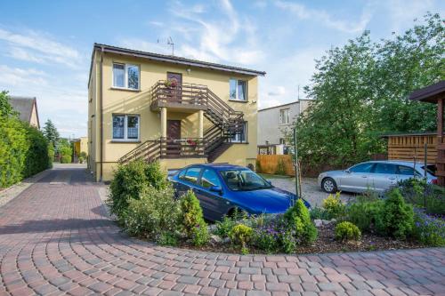 a house with two cars parked in front of it at Pokoje AGA in Mikołajki