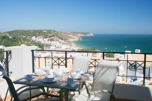 a table on a balcony with a view of the ocean at The View – Santo António Villas, Golf & Spa in Salema