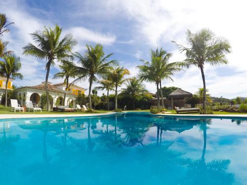 a large swimming pool with palm trees in the background at Villa Raphael in Búzios