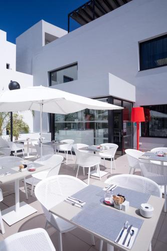 a restaurant with white tables and white chairs and umbrellas at Migjorn Ibiza Suites & Spa in Playa d'en Bossa