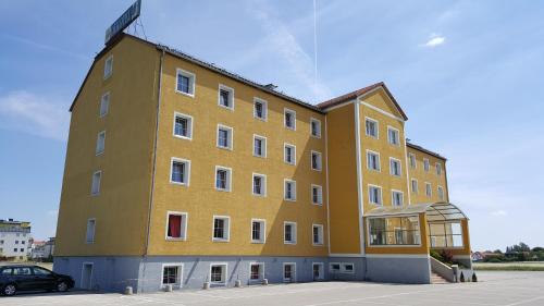 a yellow building with a car parked in a parking lot at OEKOTEL Traiskirchen in Traiskirchen