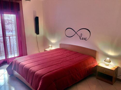 a bedroom with a red bed with the word love on the wall at Appartamento La Terrazza in Castellammare del Golfo