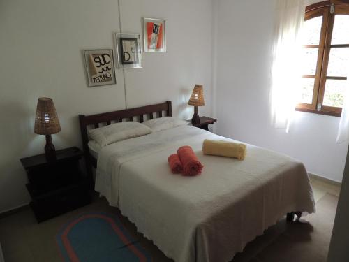 a bedroom with a bed with two red towels on it at Tô na Roça in Cunha