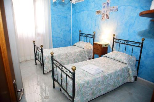 two beds in a blue room with a cross on the wall at Sant'Andrea in Tricase