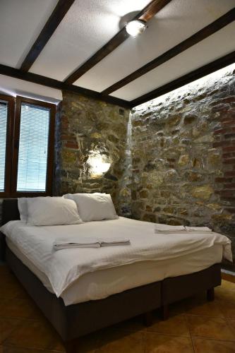 a bed in a room with a stone wall at Canyon Matka Hotel in Matka