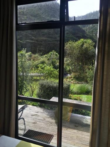 an open window with a view of a wooden deck at Piha Beachstay Accommodation in Piha