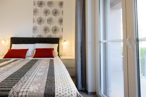 Apartment Relja في زادار: غرفة نوم بسرير ومخدات حمراء ونافذة