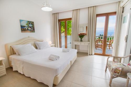 - une chambre avec un grand lit blanc et un balcon dans l'établissement Petrino, à Ambrami
