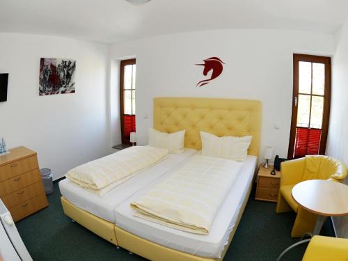 a bedroom with a large bed and a yellow chair at Hotel-Restaurant Rotes Einhorn Düren *** Superior in Düren - Eifel