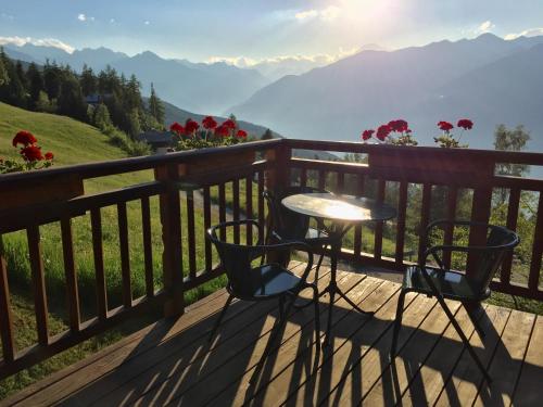 a table and chairs on a balcony with a view of mountains at Chalet D'Antan in Pila