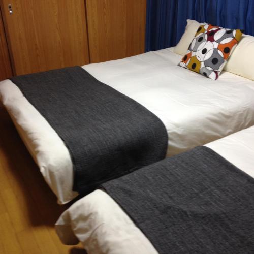 two beds in a hotel room with a blanket at Family Resort Apartment in Funabashi