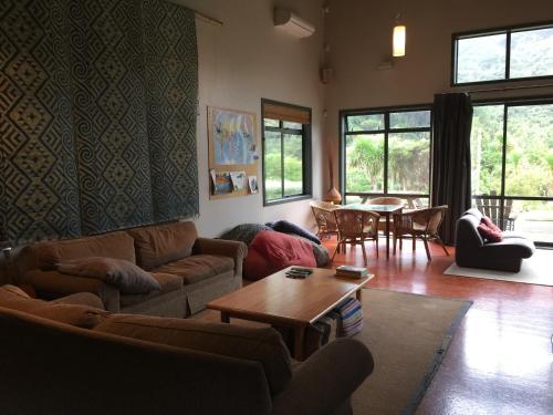 a living room with couches and a table and chairs at Piha Beachstay Accommodation in Piha