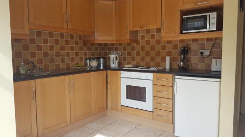 a kitchen with wooden cabinets and a white stove top oven at Coiribe House B&SelfBreakfast in Galway