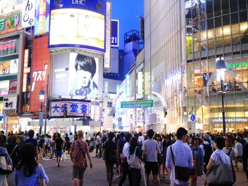 a crowd of people walking down a busy city street at night at COTO Tokyo Shibuya 2 in Tokyo