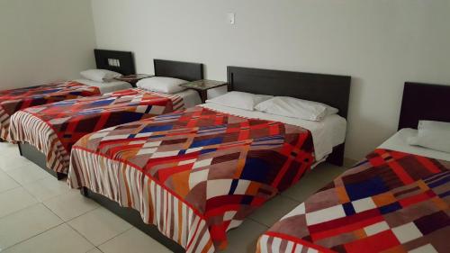 three beds in a room with colorful comforters at Hotel Vermon Armenia in Armenia
