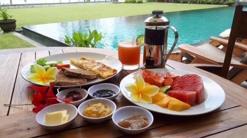 a table with a plate of food and a drink at Villa Rumah Pantai Bali in Selemadeg
