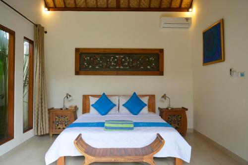 1 dormitorio con 1 cama grande con almohadas azules en Villa Mewali, en Ubud