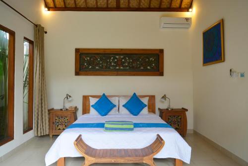 a bedroom with a large bed with blue pillows at Villa Mewali in Ubud