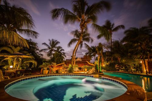 a large swimming pool with palm trees in the background at Pousada Cavalo Marinho in Pipa