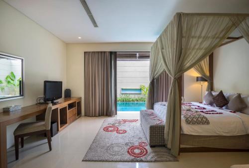 a bedroom with a bed and a desk and a television at Pradha Villas Seminyak in Seminyak