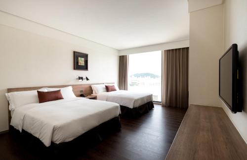 a hotel room with two beds and a flat screen tv at Just Sleep Hualien ZhongZheng in Hualien City