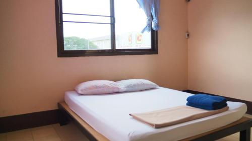 a bed with two pillows and a window in a room at Charinsup Hotel in Ban Khlong Thai Muang