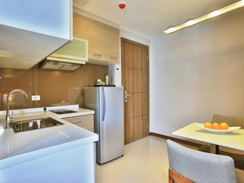 a kitchen with a sink and a refrigerator at Valero Grand Suites by Swiss-Belhotel in Manila