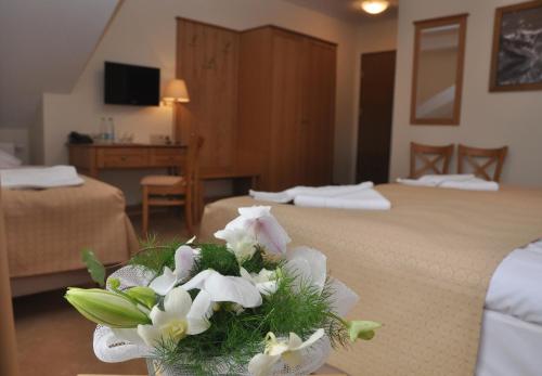 a hotel room with two beds and a bouquet of flowers at Hotel Alpejski in Polanica-Zdrój
