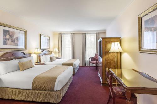 a hotel room with two beds and a desk at Canterbury International Hotel in Forest Hill