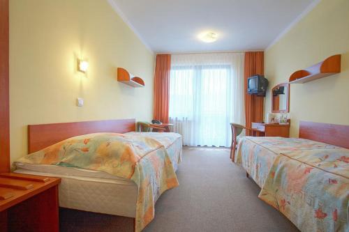 a hotel room with two beds and a television at Geovita Muszyna in Muszyna