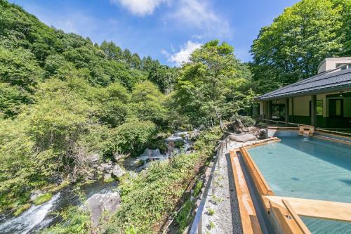 a house with a swimming pool next to a river at Tateshina Grand Hotel Takinoyu in Chino