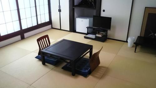Cette chambre comprend une table, une chaise et une télévision. dans l'établissement Guest House Koundo, à Nikkō