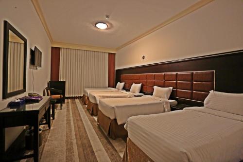 Le Bosphorus Hotel Two في المدينة المنورة: غرفة فندقية بأربعة أسرة وطاولة